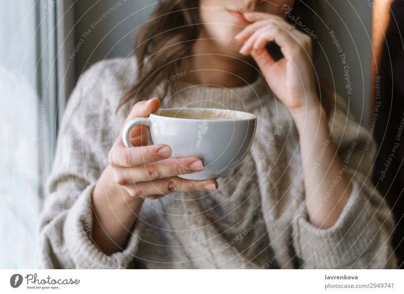 Damenhaltebecher mit Latte vor dem Fenster Selektiver Fokus Café Nahaufnahme Kaffee Tasse Getränk trinken Frau Schwache Tiefenschärfe Junge Frau heimwärts heiß