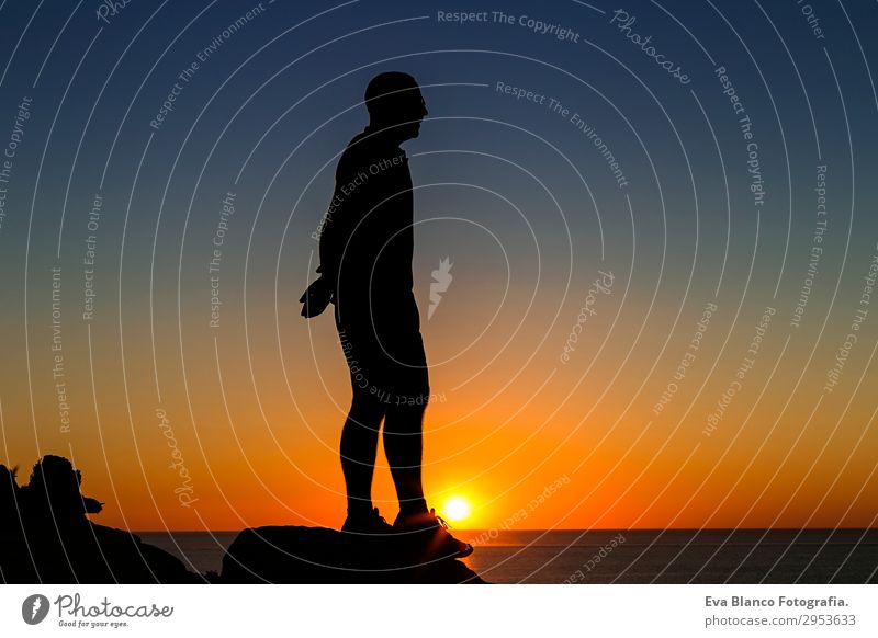 Silhouette eines jungen Mannes, der auf dem Berg steht. Lifestyle Reichtum Freude Leben Freizeit & Hobby Ausflug Abenteuer Sonne Meer Berge u. Gebirge Sport