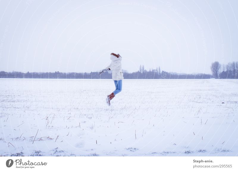 Weg vom Schnee feminin Junge Frau Jugendliche 1 Mensch Landschaft Winter schlechtes Wetter Feld Jeanshose Jacke Mantel Stiefel Kapuze springen frei einzigartig