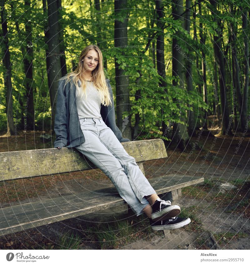 Junge Frau sitzt auf einer Bank in einem Wald Freude schön Wellness Leben Jugendliche 18-30 Jahre Erwachsene Natur Landschaft Schönes Wetter Jeanshose Jacke