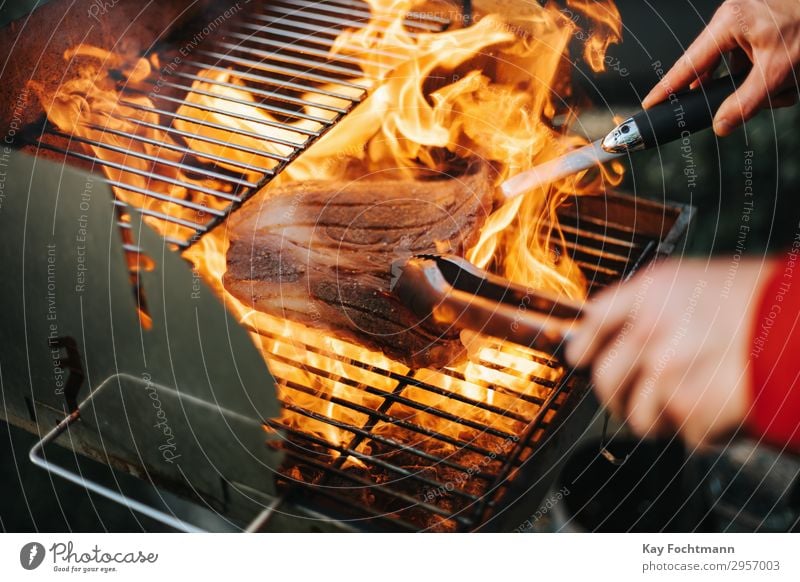 Steak umgeben von hohen Flammen auf einem Grill arbeiten Barbecue grillen Rindfleisch Beefsteak Küchenchef geschnitten Feinwäsche Entrecote teuer Fett Filet