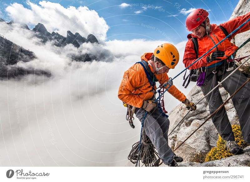 Team von Kletterern beim Abseilen. Abenteuer Klettern Bergsteigen Mann Erwachsene 2 Mensch 30-45 Jahre Wolken Unwetter Helm selbstbewußt Mut Tatkraft Höhenangst