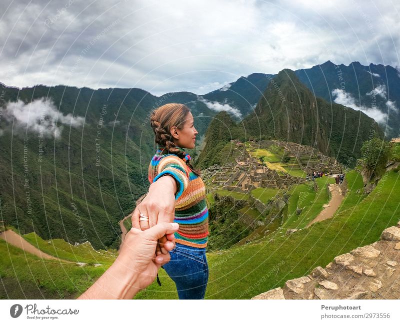 Stehendes Paar, das sich an den Händen hält und über die Terrassen von Machu Picchu, dem meistbesuchten Touristenziel in Peru, nachdenkt. Bild von hinten.