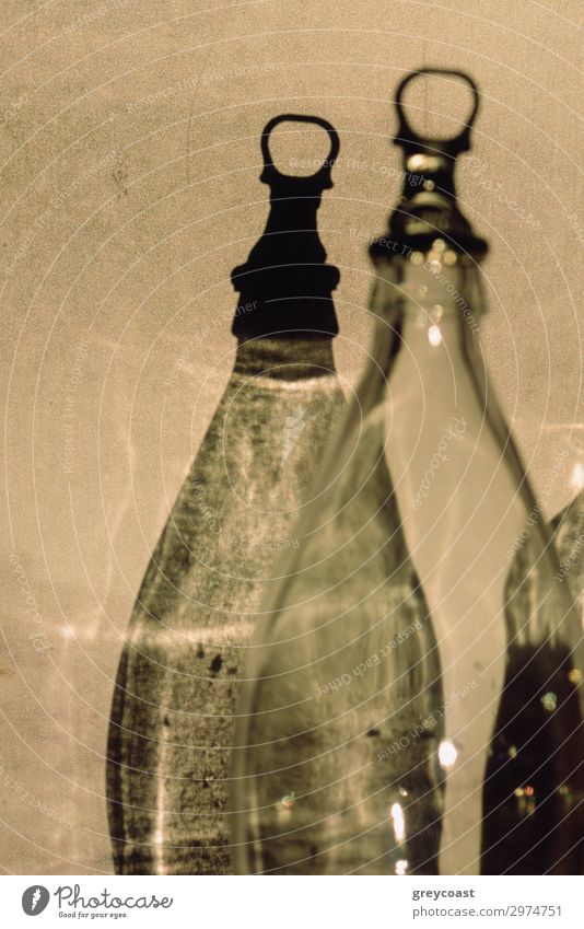 Ein Fragment einer transparenten, leeren Flasche und ihr grafischer Schatten auf einer hellen Wand schön dünn graphisch Zwilling Flaschenverschluss Bruchstück