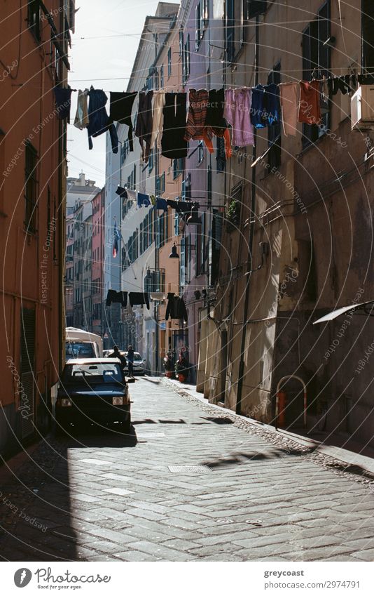 Eine sonnenbeschienene, authentische, enge Straße in Neapel mit Kleidung, die an einem Seil aufgehängt ist und über die Straße gespannt ist Lifestyle Bekleidung