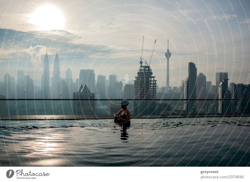 Frau genießt Stadtbild von Kuala Lumpur von Dach-Schwimmbad. Stadtszene mit Wolkenkratzern, Petronas Tower und Kuala Lumpur Tower, Malaysia Reichtum Erholung