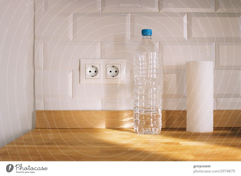Ein minimalistisches Küchenstillleben mit einem Papierhandtuch, einer Plastikflasche und einer Steckdose Häusliches Leben Wohnung Verpackung Paket Baustein dünn