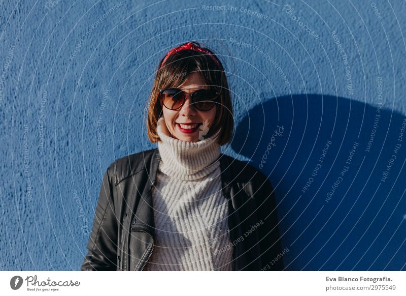 Porträt einer jungen schönen Frau im Freien auf blauem Hintergrund Lifestyle elegant Stil Freude Glück Gesicht Sonne Mensch Erwachsene Sonnenbrille brünett