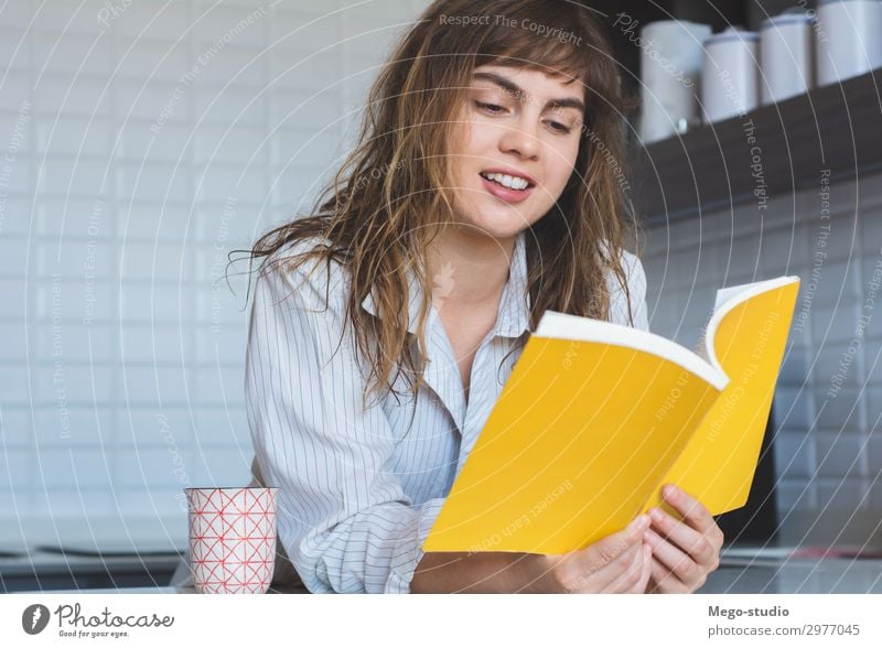 Frau, die ein Buch liest Frühstück Lifestyle Freude Glück schön Erholung lesen Haus Tisch Küche Mensch Erwachsene Denken Lächeln sitzen modern weiß Einsamkeit