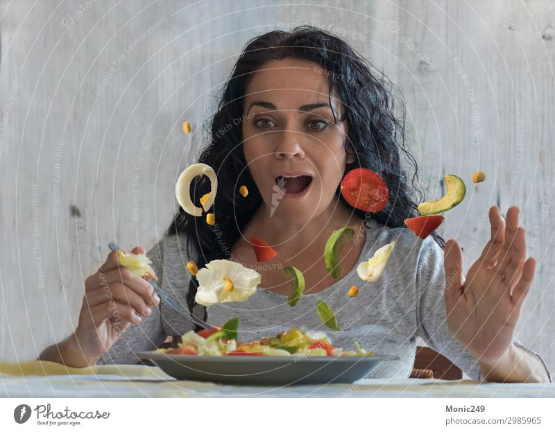 Erstaunte brünette Frau, die fliegende Gemüse in ihrem Salat beobachtet. Mittagessen Abendessen Diät Teller Gabel Lifestyle Glück Gesunde Ernährung Restaurant