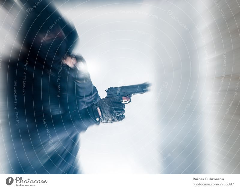 Ein Mann mit Kapuze und Maske hält eine Pistole in der Hand Überfall Räuber kriminell Einbrecher Waffe Einbruch schießen unscharf getarnt Dieb