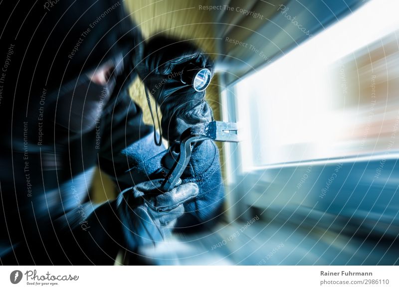 Ein Einbrecher mit Brecheisen und Taschenlampe schaut durch ein Fenster Mensch 1 Einfamilienhaus beobachten Blick warten dunkel blau Feindseligkeit Aggression