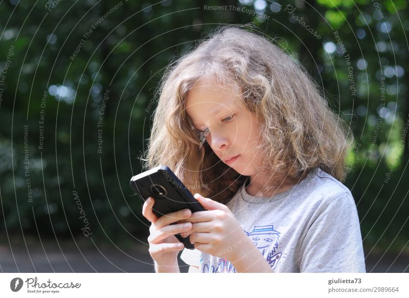 In another world | Cooler Junge mit langen Haaren vertieft in sein Handy... Kindheit Leben 1 Mensch 8-13 Jahre Sommer Park blond langhaarig Locken Kommunizieren
