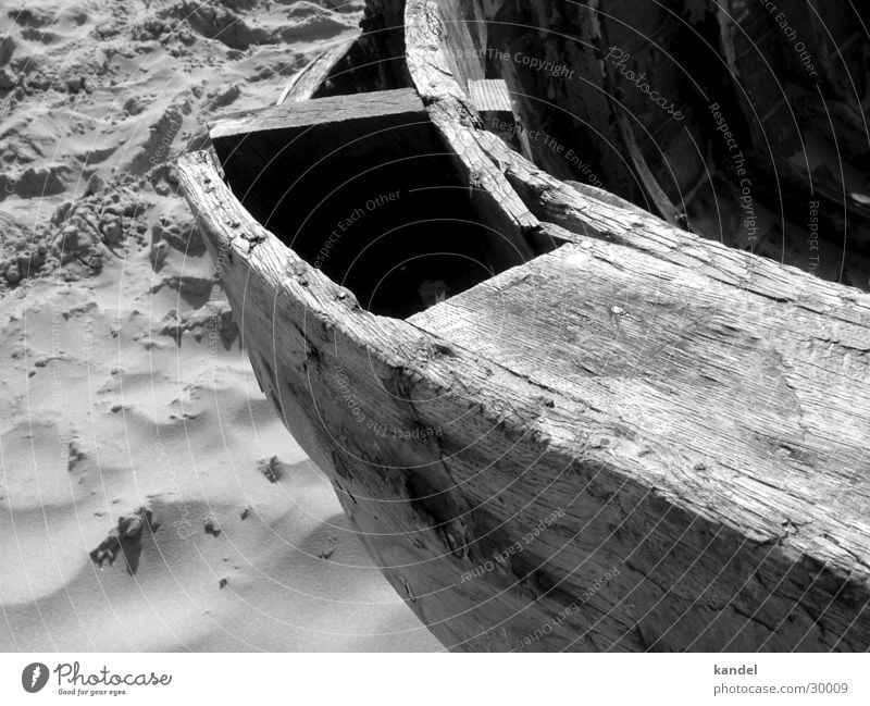 Gestrandet Wasserfahrzeug Holz Strand schwarz weiß morsch Meer historisch alt Sand Schiffsplanken Kontrast Wind