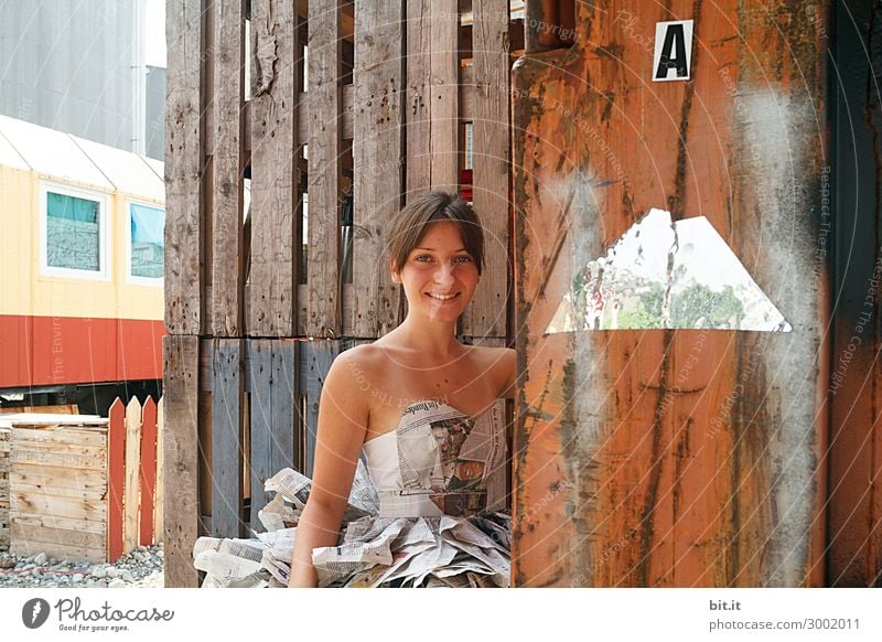 Junge Frau mit Kleid aus Zeitungen, vor Holzwand. feminin Jugendliche Erwachsene Wahrheit Medien Druckerei Zeitschrift Kunst Körperkunst Information Oberkörper
