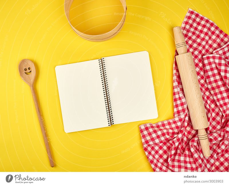 offenes Notizbuch und Küchenzubehör aus Holz Löffel Werkzeug Buch Natur Sieb Papier schreiben natürlich oben gelb rot weiß Hintergrund blanko Entwurf Koch