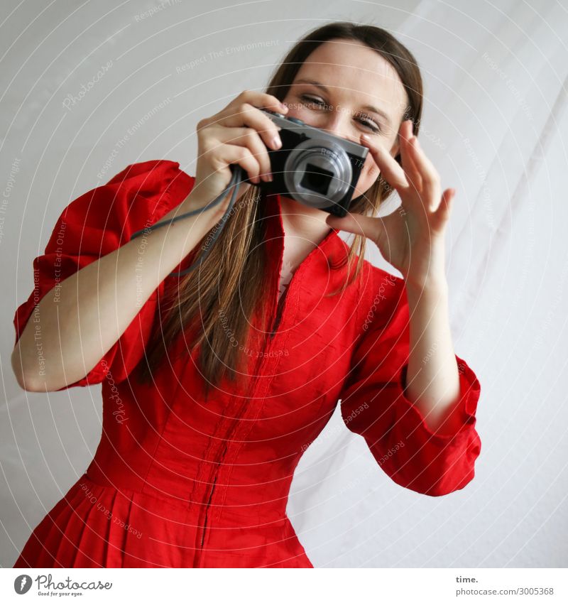 Frau im roten Kleid mit Kamera Gardine Fotokamera feminin Erwachsene 1 Mensch Stoff brünett langhaarig beobachten festhalten lachen Blick Fröhlichkeit schön