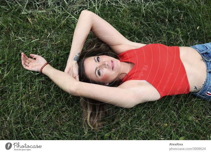 Junge Frau liegt im Gras Lifestyle Glück schön harmonisch Wohlgefühl Jugendliche 18-30 Jahre Erwachsene Pflanze Schönes Wetter Wiese Top bauchfrei rot brünett
