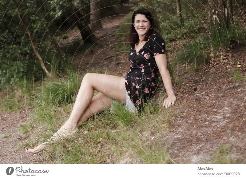 Portrait einer großen jungen Frau, die lächelnd an einer Waldlichtung sitzt Lifestyle Freude Glück schön Leben Junge Frau Jugendliche Beine 18-30 Jahre