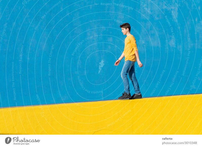 Junger Junge trägt lässige Kleidung zu Fuß gegen eine blaue Wand in einem sonnigen Tag Lifestyle Sommer Sonne Mensch maskulin Kind Mann Erwachsene Jugendliche 1