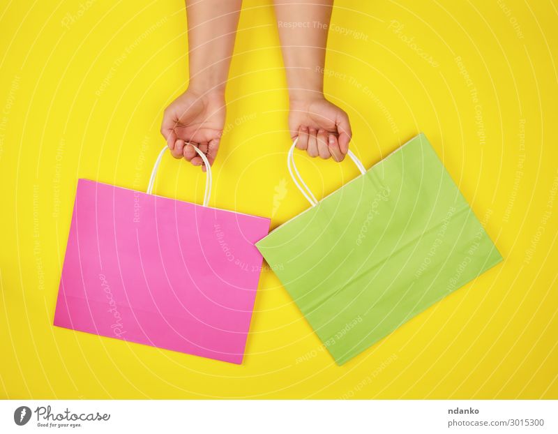 zwei Hände mit Papiertragetaschen Lifestyle kaufen Stil Design Business Hand Container Mode Verpackung Paket festhalten modern neu gelb grün rosa Farbe