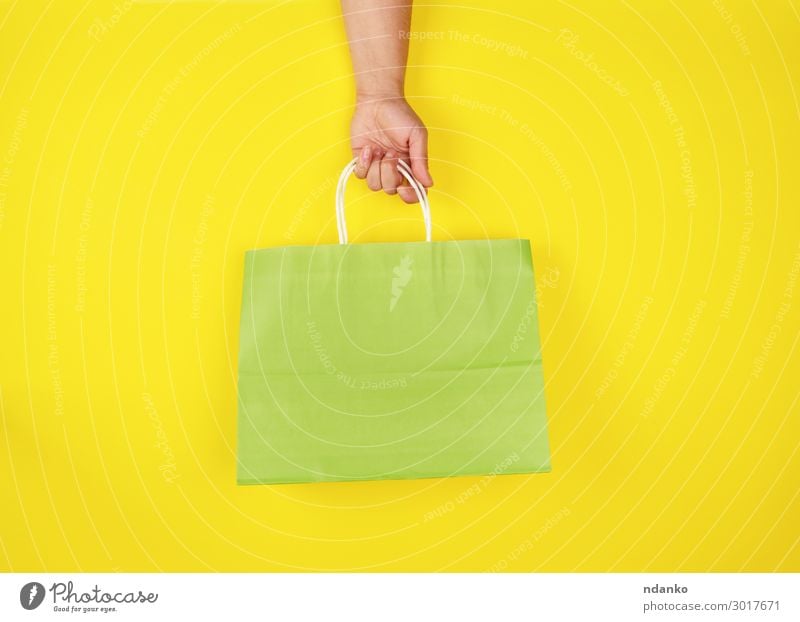 weibliche Hand mit einer grünen Papiertragetasche Lifestyle kaufen Stil Design Business Mensch Frau Erwachsene Container Mode Verpackung Paket modern neu gelb