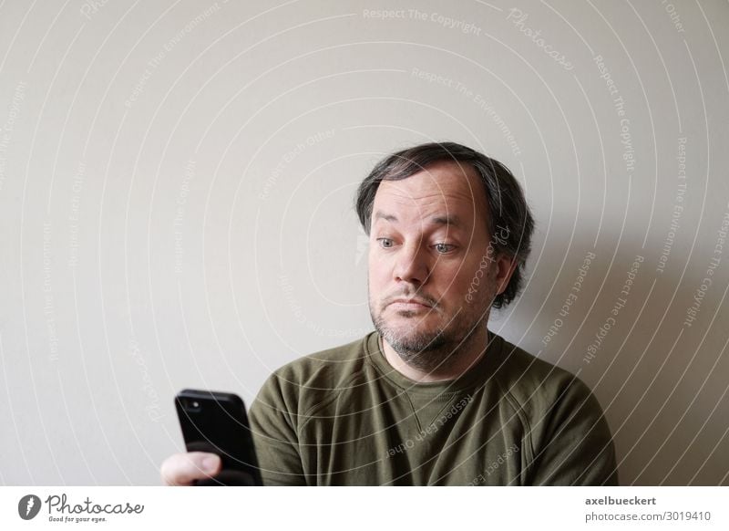 Mann schaut verdutzt auf Smartphone Lifestyle Telefon Handy PDA Technik & Technologie Unterhaltungselektronik Telekommunikation Internet Mensch Erwachsene 1