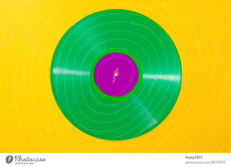 Schallplatte aus grünem Vinyl vor gelbem, neutralen Hintergrund Musik Musik hören trendy retro verrückt violett Farbe einzigartig modern Nostalgie Farbfoto