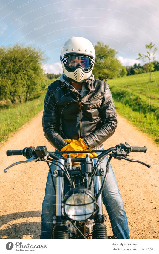 Mann mit Helm auf einem Custom-Motorrad Lifestyle Mensch Erwachsene Gras Verkehr Straße Wege & Pfade Fahrzeug Mode Jeanshose Handschuhe sitzen warten