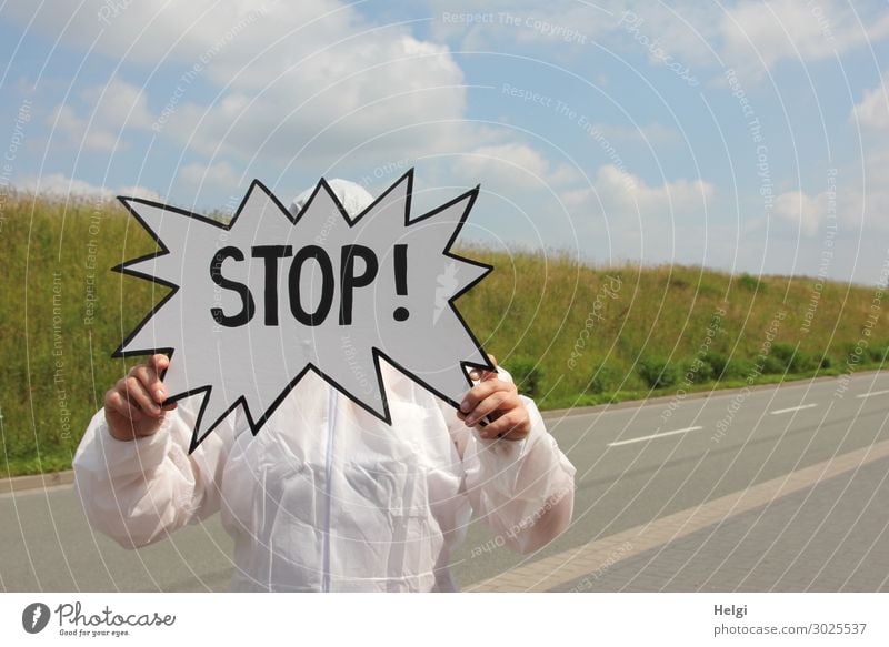 Person im Schutzanzug steht auf einer Straße und hält ein Schild "Stop" in den Händen Mensch Erwachsene Arme Hand Finger 1 Umwelt Natur Landschaft Pflanze