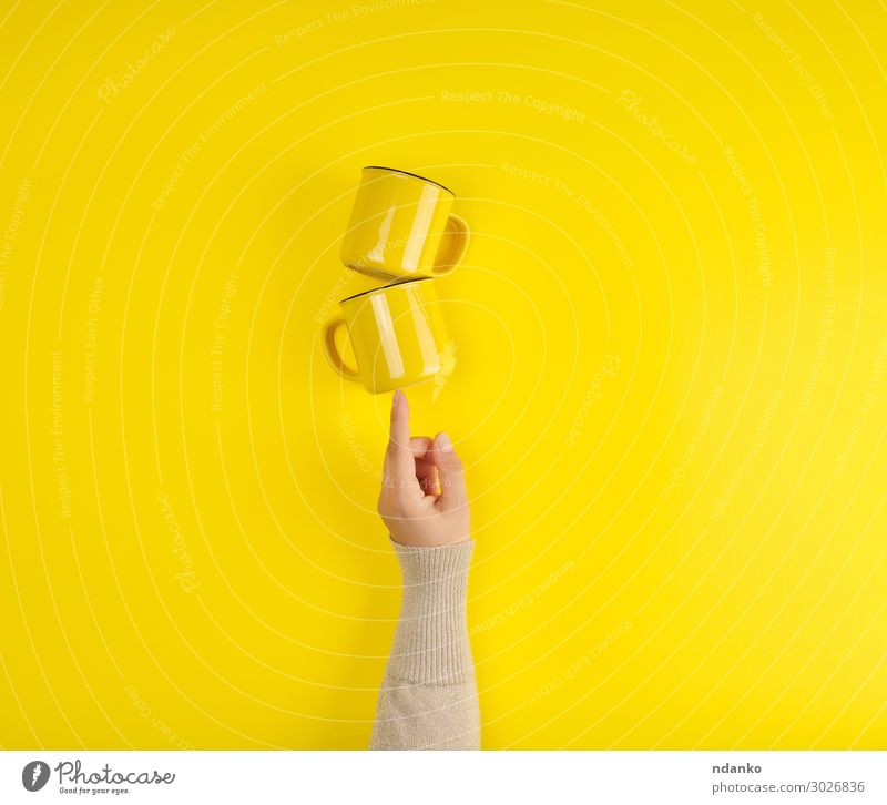 zwei gelbe Keramikbecher werden von einer weiblichen Hand getragen. Frühstück Kaffee Tee Tasse Küche Arme Finger heiß hell Sauberkeit Farbe abstützen Halt