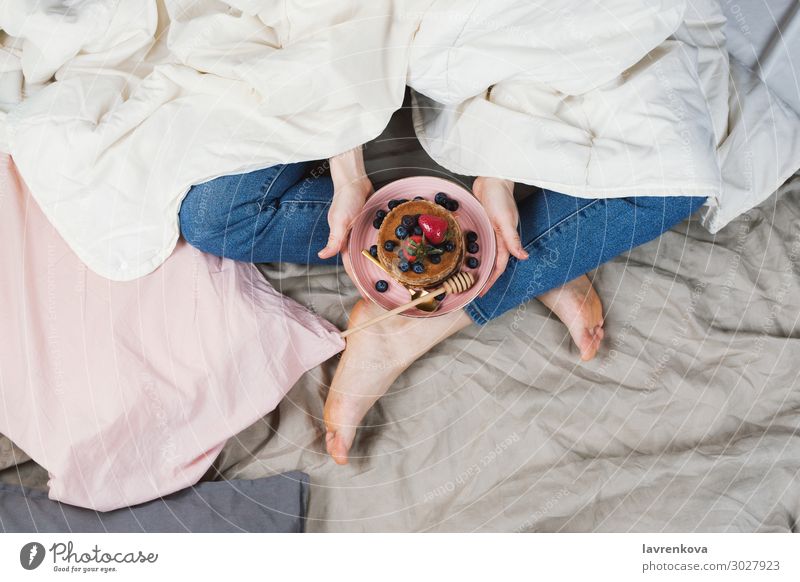 Frau in ihrem Bett Halteplatte mit Pfannkuchen Bettwäsche Blaubeeren Frühstück Lebensmittel Gesunde Ernährung Speise Foodfotografie frisch Hand Gesundheit