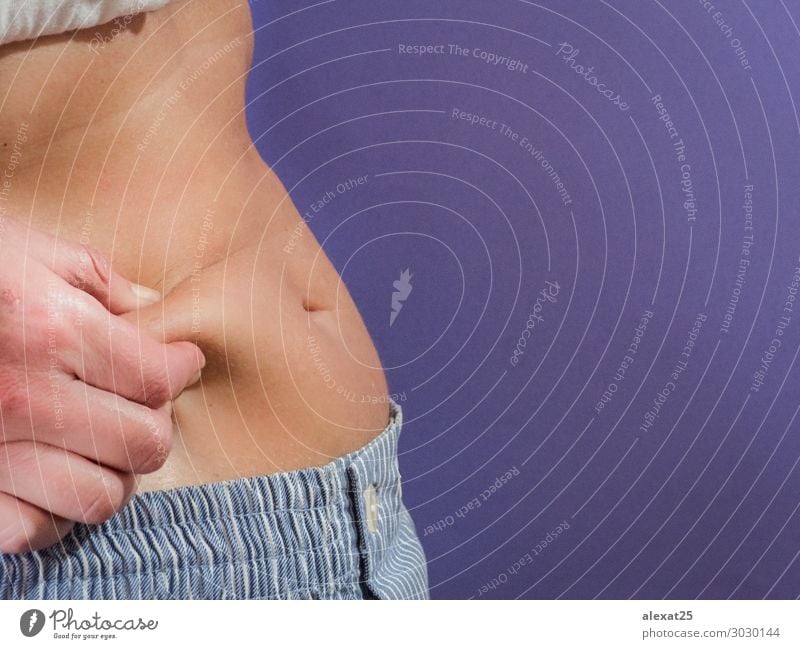 Mittelschnitt einer Frau, die Fett in ihrem Bauch testet. Diät Lifestyle Körper Haut Behandlung Übergewicht Mensch Erwachsene Hand Fitness weiß Unterleib