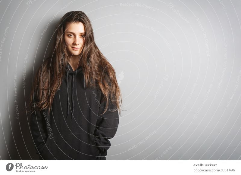 junge Frau mit schwarzem Pullover, die sich an eine graue Wand lehnt. Lifestyle Stil Mensch Junge Frau Jugendliche Erwachsene 1 18-30 Jahre Mode brünett
