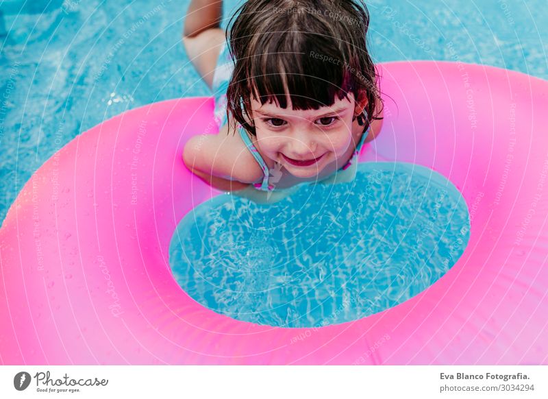 schönes Kind Mädchen, das auf rosa Donuts in einem Pool schwimmt. Lifestyle Freude Glück Erholung Schwimmbad Freizeit & Hobby Ferien & Urlaub & Reisen Sommer