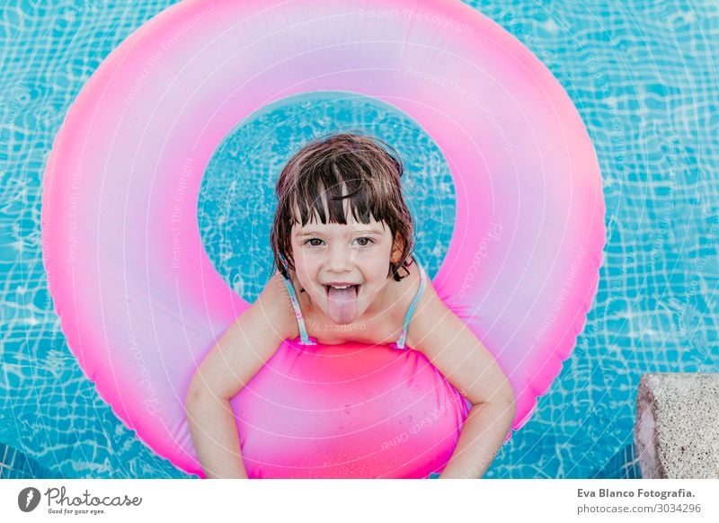 schönes Kind Mädchen, das auf rosa Donuts in einem Pool schwimmt. Lifestyle Freude Glück Erholung Schwimmbad Freizeit & Hobby Ferien & Urlaub & Reisen Sommer