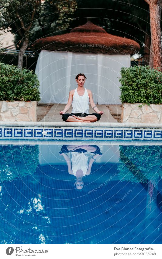 Frau, die Yoga am Swimmingpool macht. Yoga und Achtsamkeit Lifestyle schön Körper Erholung ruhig Meditation Spa Schwimmbad Freizeit & Hobby