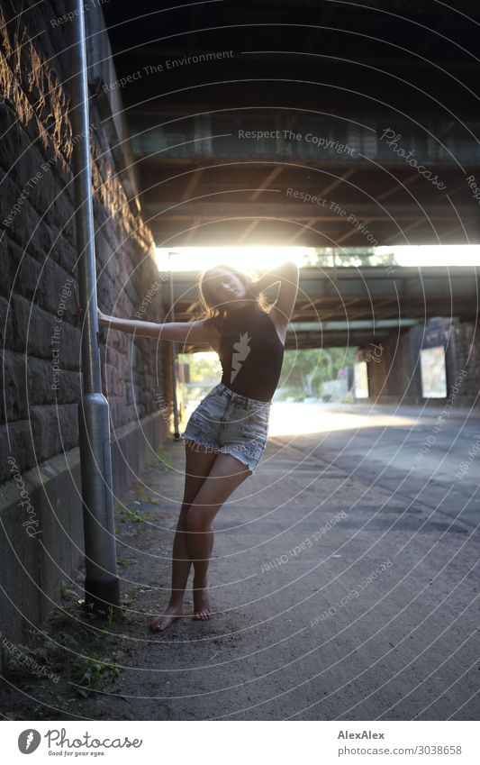 Junge Frau schwingt an einer Laterne im Gegenlicht unter eine Brücke an einer Straße Lifestyle Stil Freude schön Leben Laternenpfahl Mauer Jugendliche