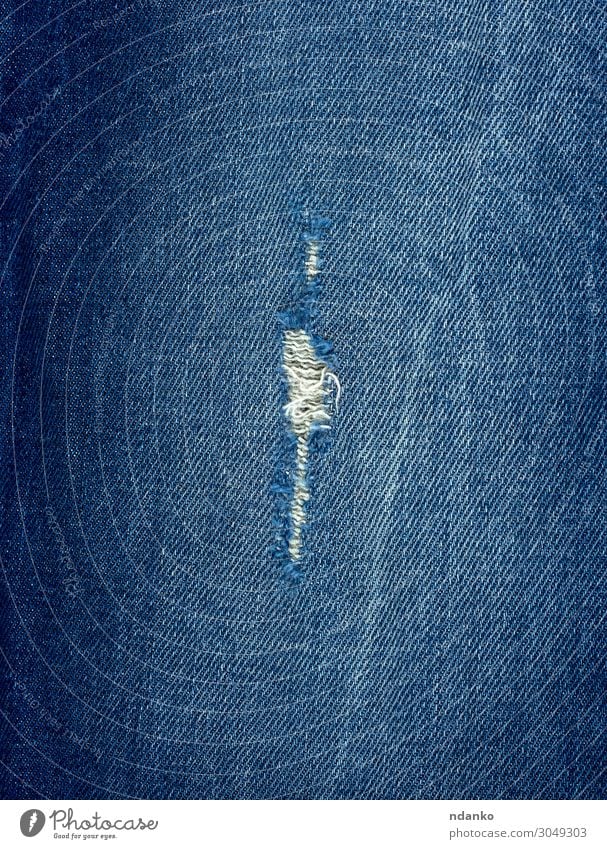 Fragment aus Blue Jeansstoff mit einem Loch Stil Design Mode Bekleidung Hose Jeanshose Stoff alt blau Farbe Hintergrund Leinwand lässig Baumwolle Schaden Sehne