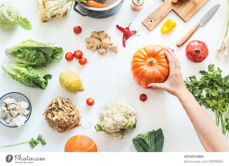Hand haltet Kürbis auf Tisch mit Gemüse Lebensmittel Kräuter & Gewürze Ernährung Bioprodukte Vegetarische Ernährung Diät Geschirr Topf Messer kaufen Stil Design