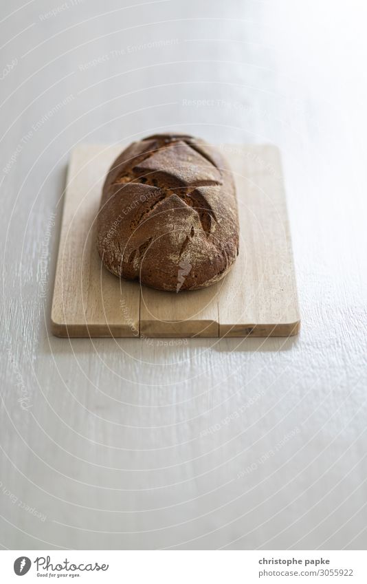Laib Brot auf Holzbrett Lebensmittel frisch Gesundheit Teile u. Stücke backen Bäckerei ungeschnitten Farbfoto Innenaufnahme Nahaufnahme Menschenleer