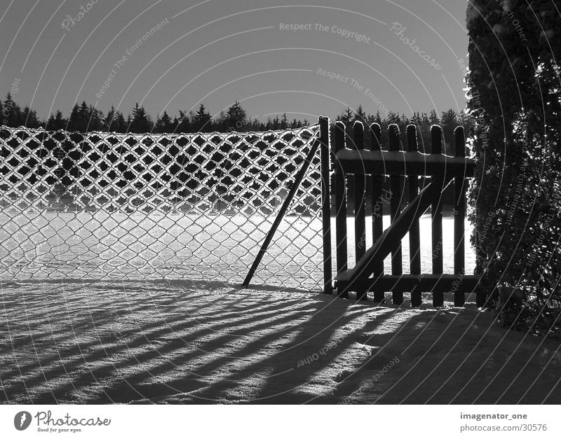 0005 Zaun Licht Schatten Schnee Eis Schwarzweißfoto