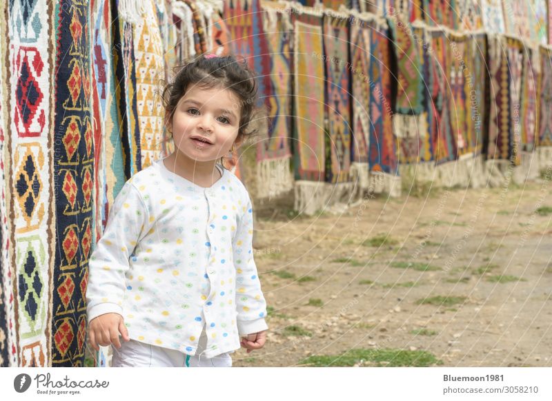 Porträt eines kleinen Mädchens vor einem bunten Kelim mit geometrischen Mustern Lifestyle Reichtum schön stricken Tourismus Kind Handel Business Mensch