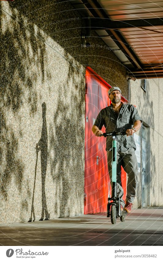 Mann mit Mütze fährt E-Roller Lifestyle kaufen Leben Ausflug Mauer Wand Fassade Verkehr Verkehrsmittel Verkehrswege Fußgänger Wege & Pfade Fahrzeug