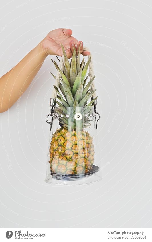 Hand hält frische reife Ananas in einem transparenten Plastikbeutel. Lifestyle kaufen Stil Freizeit & Hobby Ferien & Urlaub & Reisen Sommer Finger Mode