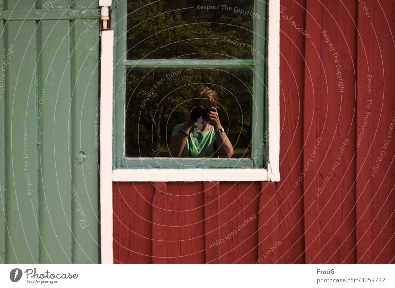 Selfi im Fenster Wand Fassade Holz Gebäude Spiegelung Bäume fotografierend Frau Fotoapparat Hände Gesicht verdeckt Uhr Armband Kette rot grün weiß