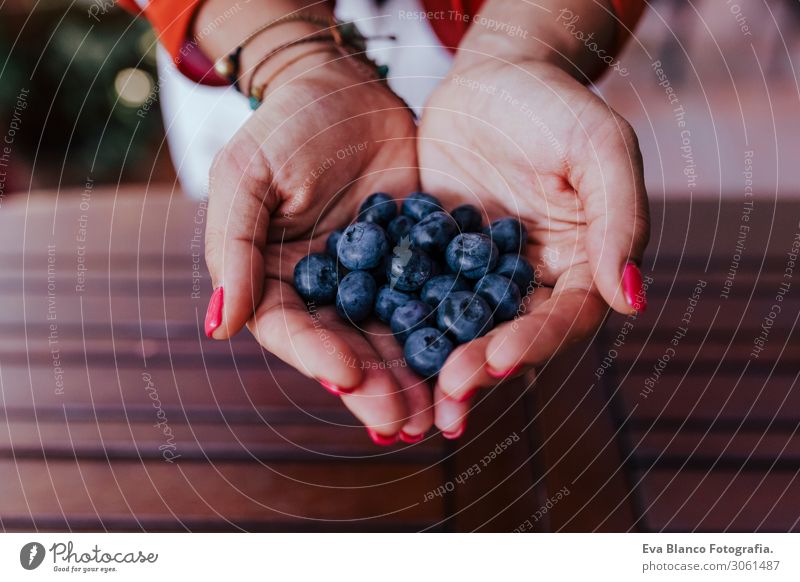 eine junge Frau, die eine Schüssel mit Blaubeeren hält. Sie bereitet ein gesundes Rezept mit verschiedenen Früchten, Wassermelone, Orange und Brombeeren vor. Verwendung eines Mixers. Hausgemacht, drinnen, gesunde Lebensweise
