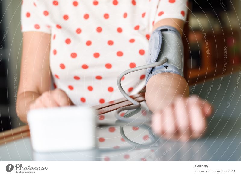 Frau, die zu Hause ihren eigenen Blutdruck misst. Gesundheitswesen Krankheit Medikament Prüfung & Examen Bildschirm Werkzeug Mensch Erwachsene Arme 1