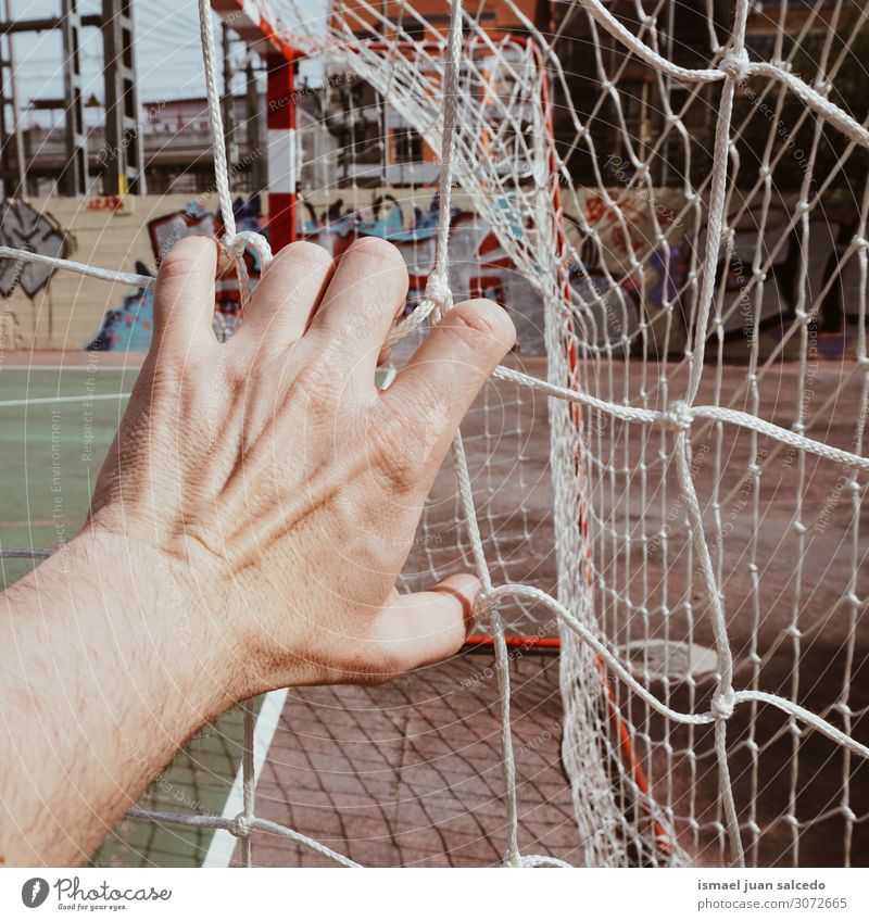 manuelles Greifen eines Fußball-Seilnetzes auf dem Feld Hand Mann Mensch Finger Körper Arme Tennisnetz Internet Sportgerät gebunden verwickelt Straße
