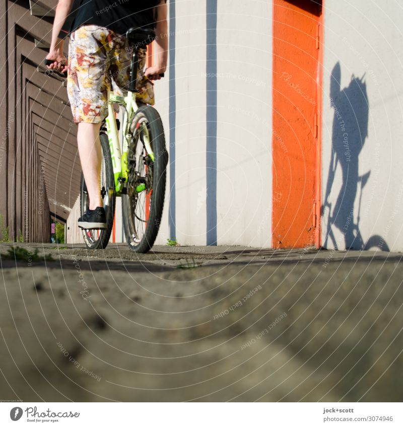 Radler mit Schattenspiel Fahrradtour Beine Wand Kolonnaden Boden Mountainbike Shorts Turnschuh fahren lang viele Gefühle erleben Mobilität Fahrradfahren Muster